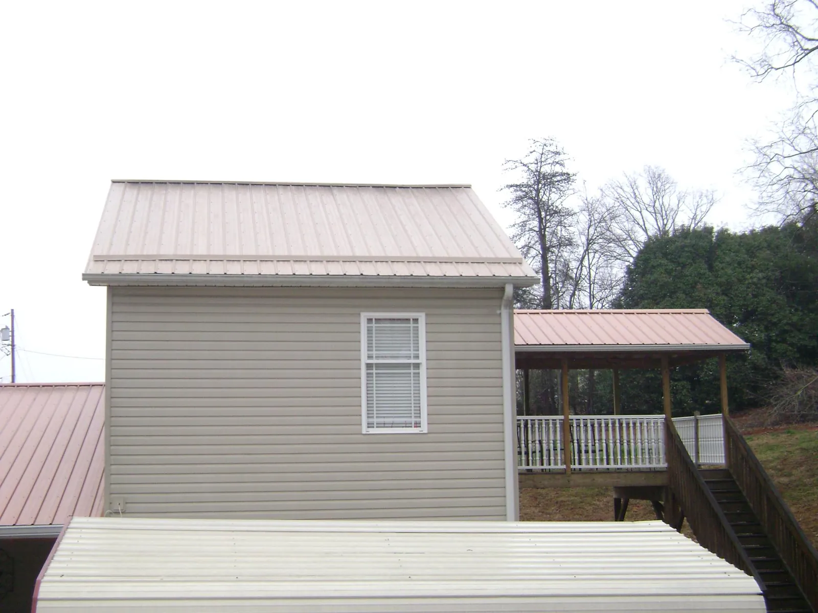 Tan metal roofs on a two story addition and attached porch, from a Roof Replacement job in Cascade
